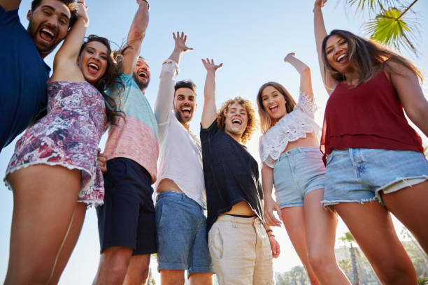 istock Laughing group of friends raising hands together laughing 868854028