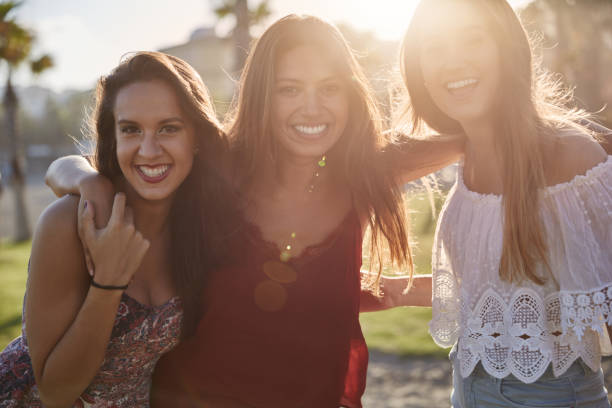 istock Three happy girls standing together in sunlight smiling 868857442