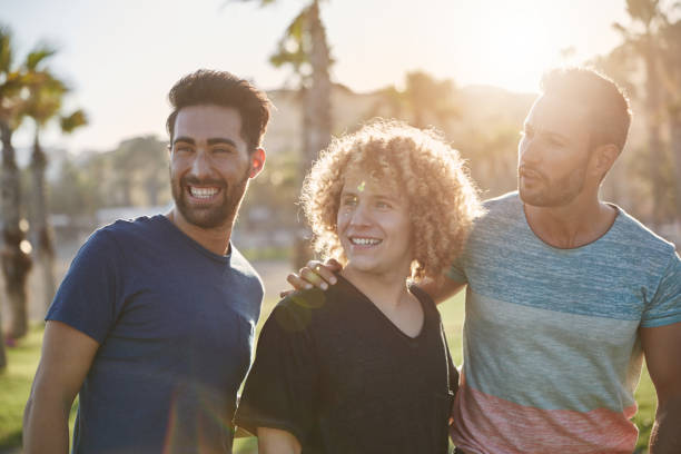 istock Three happy male friends standing outside looking away 868860434