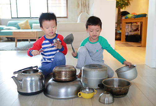 Two brother playing on floor with pots and pans