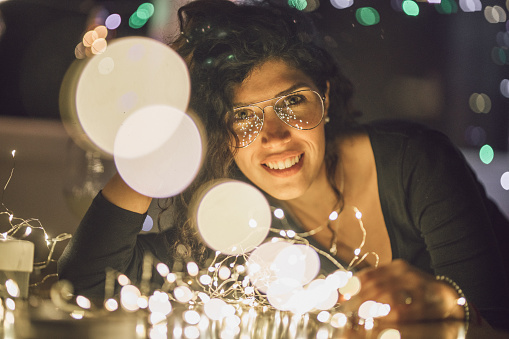 Woman at home on the new year's eve surrounded by christmas lights