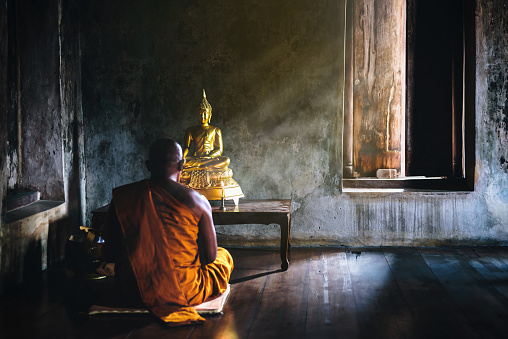 Un monje es adorar y meditar ante el Buda de oro como parte de las actividades budistas. Centrarse en el Buda photo