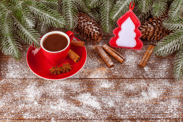 istock Christmas banner with green tree, cones, red cup with hot chocolate, felt decorations, cinnamon on wooden background 868895826