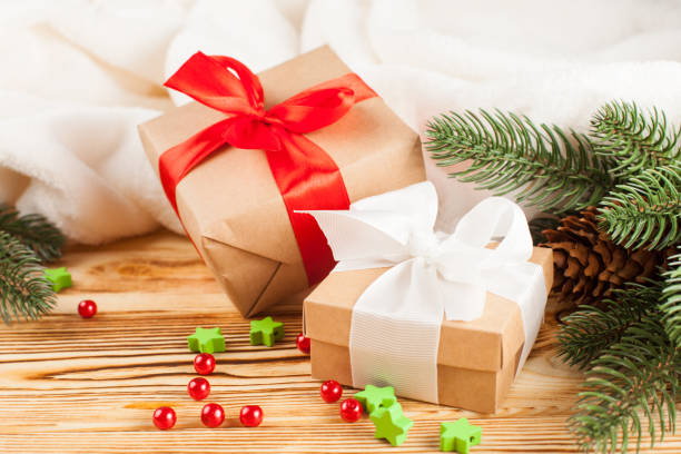istock Craft gift boxes with color ribbon and bow, green Christmas tree, decorations, white plaid on wooden background. Xmas and New Year congratulation card, banner, flyer. 868895976