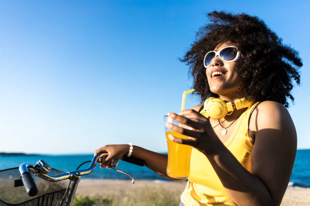 istock Cheerful african woman drinking yellow cocktail on beach 868896184