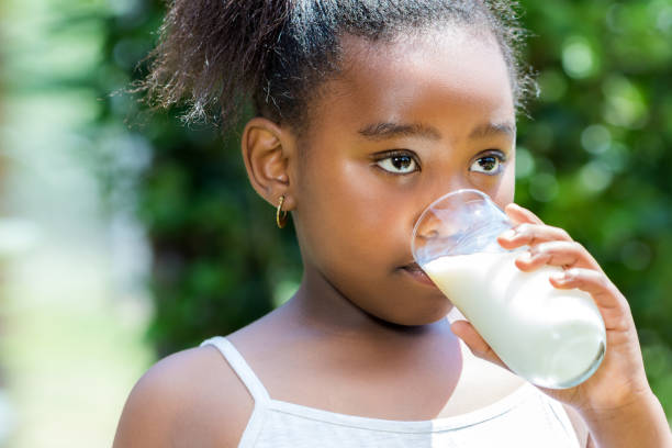 little african girl drinking milk outdoors. - milk child drinking little girls imagens e fotografias de stock