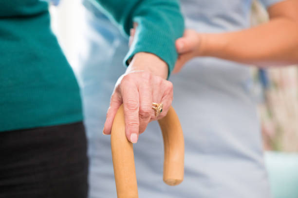 年配の女性の手とバック グラウンドで介護福祉士の杖 - senior adult home caregiver care community outreach ストックフォトと画像