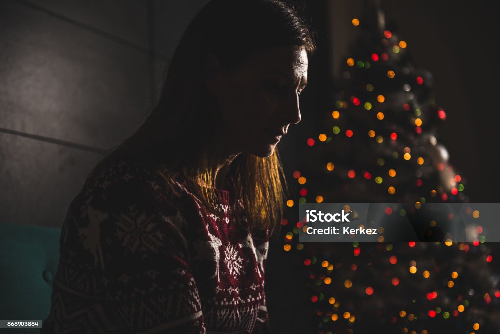 Lonely women sitting at home during christmas Lonely women sitting on the the sofa at home during christmas Christmas Stock Photo