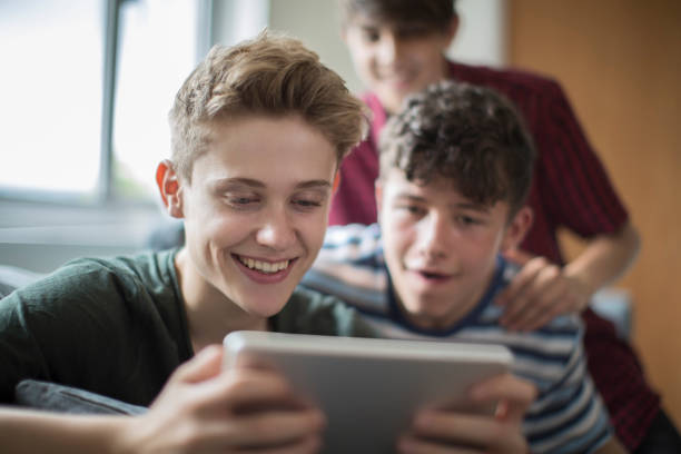 tres adolescentes jugando en digital tablet en casa - three boys fotografías e imágenes de stock