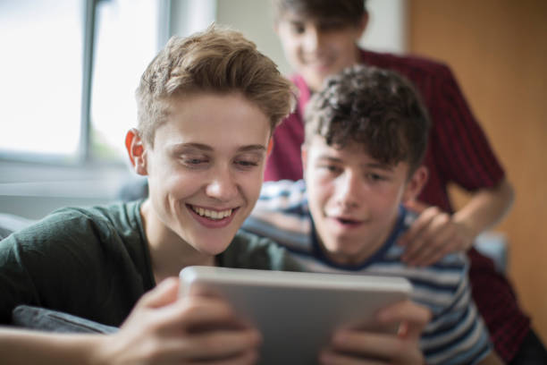 trois adolescents jouant le jeu numérique comprimé à la maison - three boys photos et images de collection