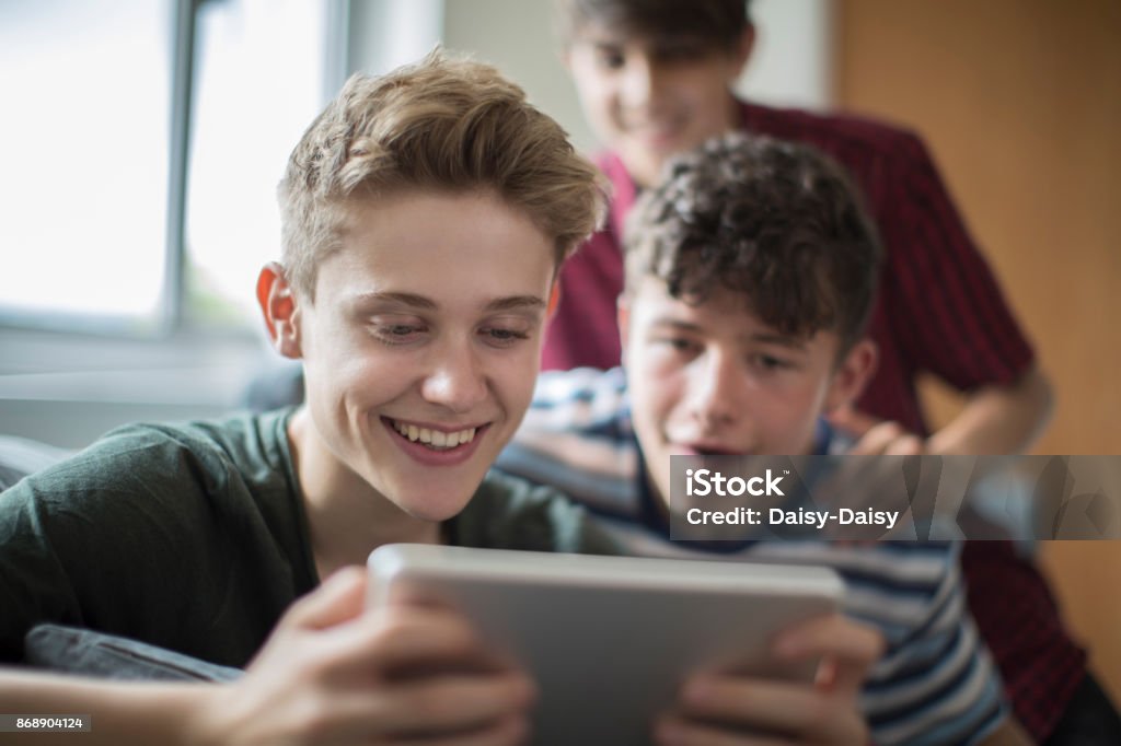 Three Teenage Boys Playing Game On Digital Tablet At Home Teenager Stock Photo