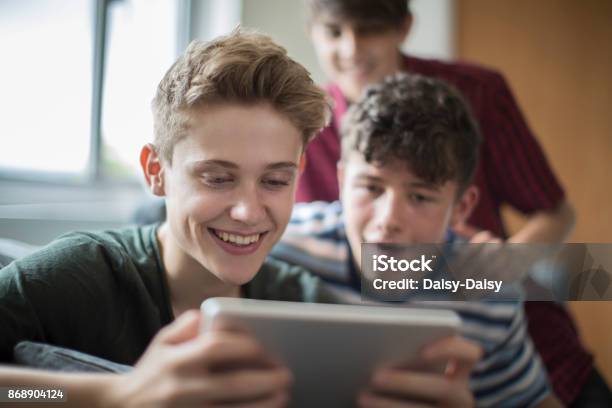 Three Teenage Boys Playing Game On Digital Tablet At Home Stock Photo - Download Image Now