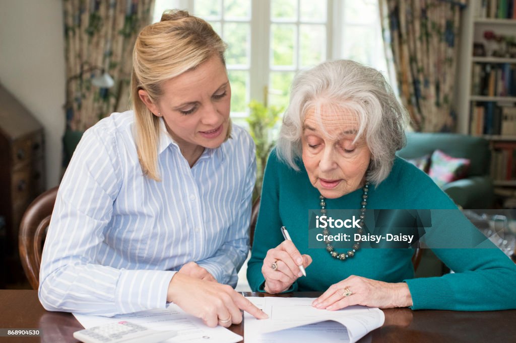 Woman Helping Senior Neighbor With Paperwork Senior Adult Stock Photo