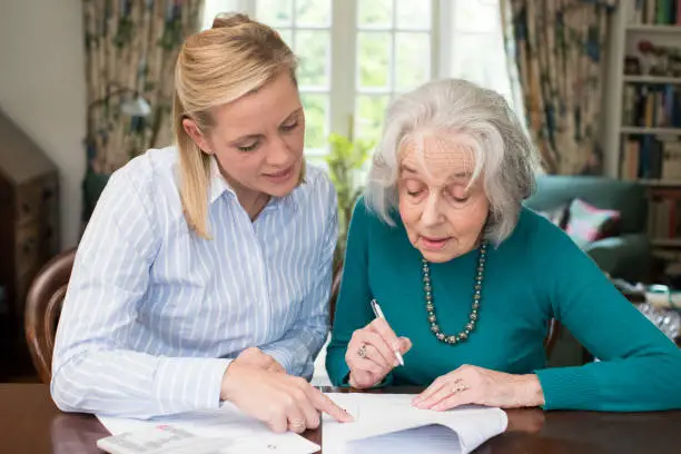 Photo of Woman Helping Senior Neighbor With Paperwork