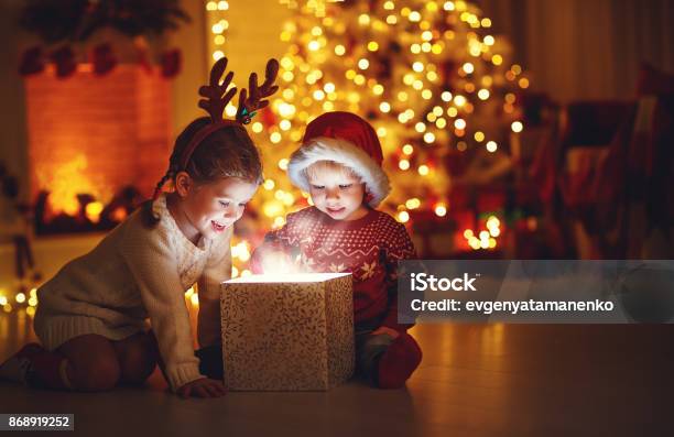 Feliz Navidad Niños Felices Con Un Regalo Mágico En Casa Foto de stock y más banco de imágenes de Niño