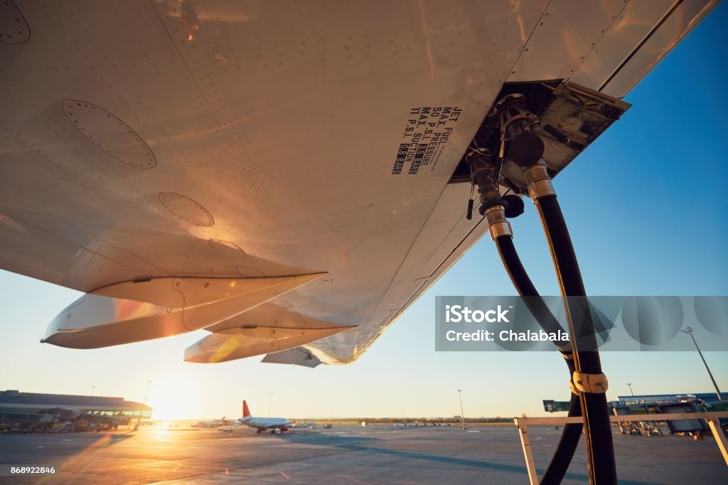 Refueling of the airplane Amazing sunset at the airport. Refueling of the airplane before flight. Airplane Stock Photo