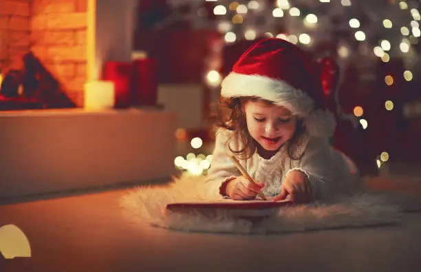 Photo of child girl writing letter santa home near Christmas tree
