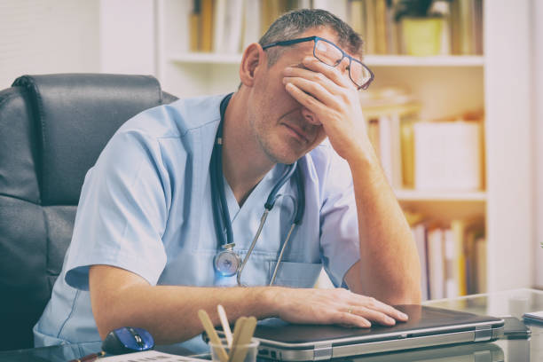 overworked doctor in his office - medical problems imagens e fotografias de stock