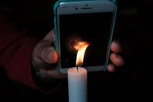 Berlin, Germany - October 12, 2017: iPhone Apple Smartphone over the flame of a burning candle
