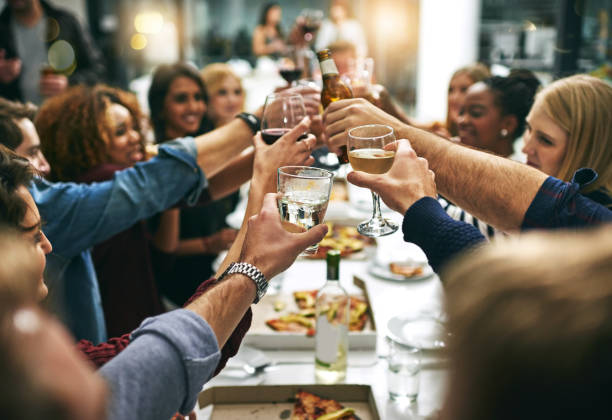 Here's to tonight Cropped shot of a group of young friends toasting during a dinner party at a restaurant celebratory toast photos stock pictures, royalty-free photos & images