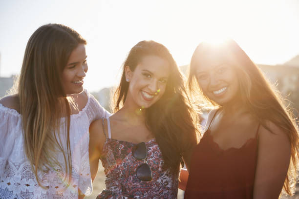 istock Three pretty female friends standing together on beach smiling 868944092