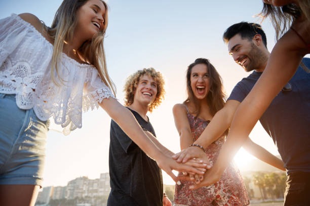 istock Happy friends holding hands together in sunlight laughing 868945342