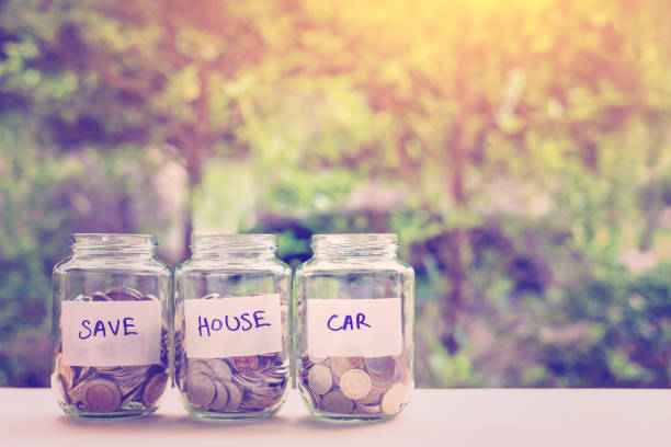 Saving money for house and car concept : Coins in glass jars. Ideas of saving for a down payment on a car or house which allow buyers to use that down payment to reduce overall cost of borrowing. Saving money for house and car concept : Coins in glass jars. Ideas of saving for a down payment on a car or house which allow buyers to use that down payment to reduce overall cost of borrowing. deposit bottle stock pictures, royalty-free photos & images