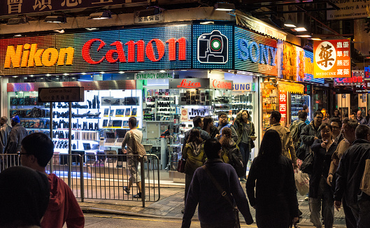 Hong Kong, China - The streets busy with people at night outside a large photographic equipment store in Kowloon.