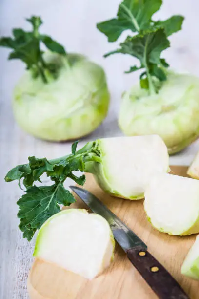 Chopped kohlrabi and knife on chopping board on a wooden table, top view.  Delicious cabbage close-up, healthy eating.