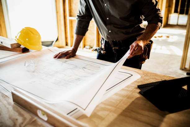 Home Building Building contractor looking over blueprints at home construction site. contractor stock pictures, royalty-free photos & images