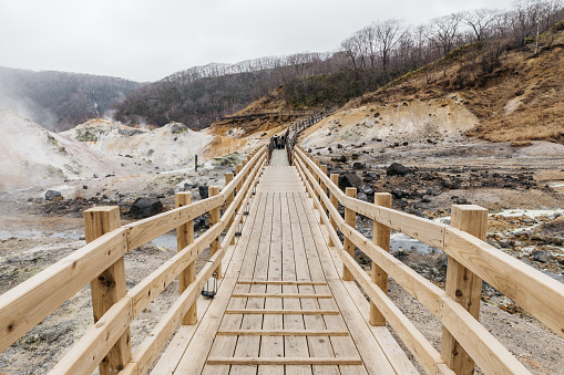 Wooden walk way at Noboribetsu Jigokudani (Hell Valley): The volcano valley got its name from the sulfuric smell, extremely high heat and steam spouting out of the ground in Hokkaido, Japan.