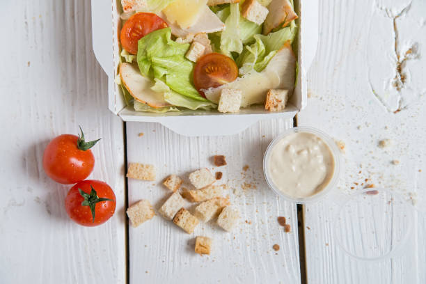 istock Caesar salad in box on white wooden surface 868959872