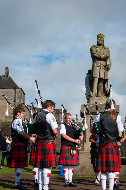 band von pipers spielen vor der statue von robert the bruce in stirling castle in sirling, schottland, vereinigtes königreich - robert bruce stock-fotos und bilder