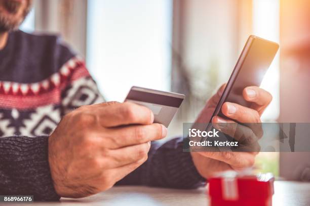 Men Holding Credit Card And Using Smart Phone At Home Office Stock Photo - Download Image Now