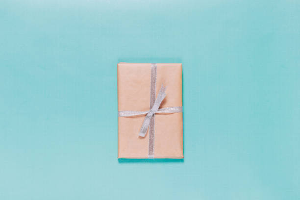 Minimalistic top view of a closed blue hardcover book on a wooden table, with soft focus greenery in the foreground. The composition combines natural elements with a clean, flat layout, making it ideal for use in educational, publishing, or digital mockup themes.