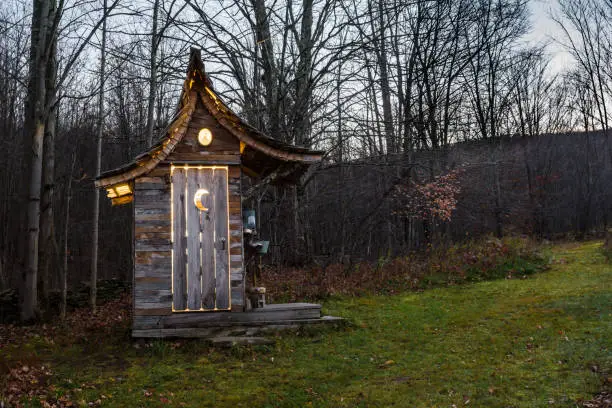 A cute glamping outhouse illuminated at night.