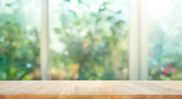 Photo of Wood table on blur of window with garden flower background
