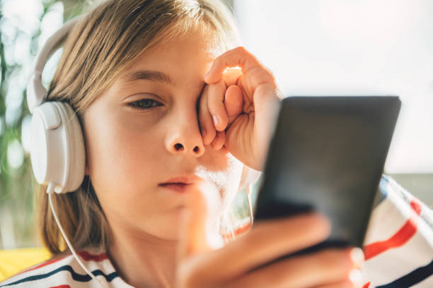 niña cansada con los auriculares con el teléfono inteligente - frotarse los ojos fotografías e imágenes de stock