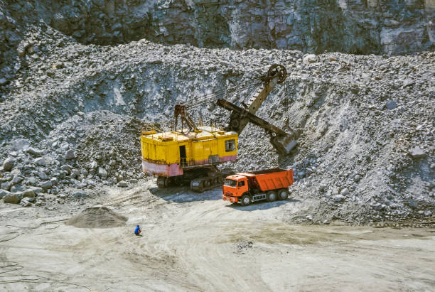 istock huge excavator, truck and man standing next on granite quarry 869003896