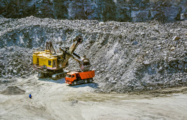 istock huge excavator, truck and man standing next on granite quarry 869003946