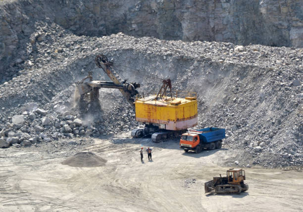 istock huge excavator, truck and man standing next on granite quarry 869003996