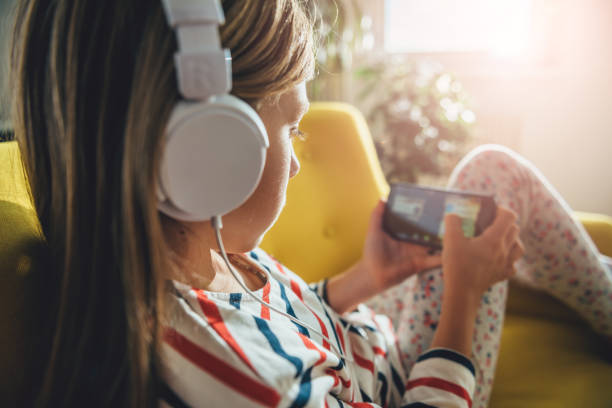 istock Little girl sitting on sofa and using smart phone 869004486