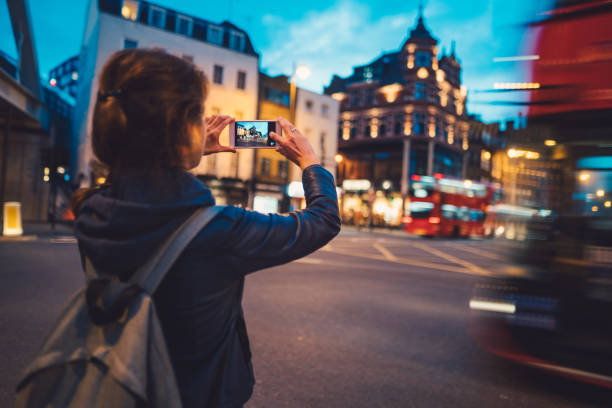 Tourist in London taking photos Young woman in London taking photos with smartphone bus photos stock pictures, royalty-free photos & images