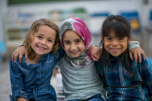 Little Muslim girl and her friends enjoy a day at school together. Little Muslim girl wearing a hijab is enjoying the day at school with her friends. pics of a cute muslim outfits stock pictures, royalty-free photos & images