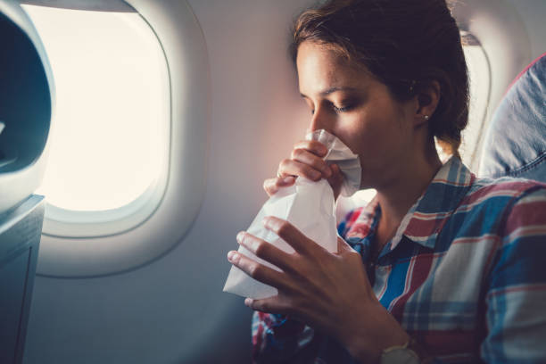 Sick woman with nausea in the airplane Young woman feeling bad during a flight and breathing in vomit bag terrified stock pictures, royalty-free photos & images