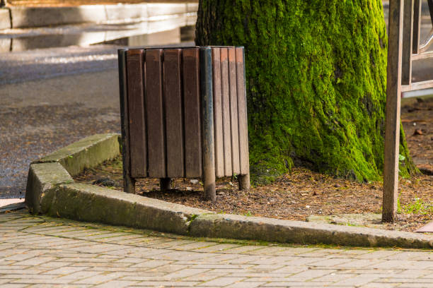 Trash can near tree trunk Wooden trash can near the tree trunk on the lawn closeup kerbstone stock pictures, royalty-free photos & images