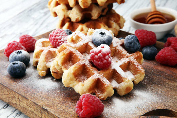 tradicionales waffles belgas con arándanos frescos, azúcar y frambuesas - wafer fotografías e imágenes de stock