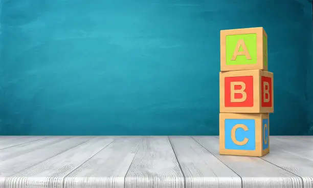 Photo of 3d rendering of a three toy blocks standing on a wooden desk in one tower with letters A, B and C on them.