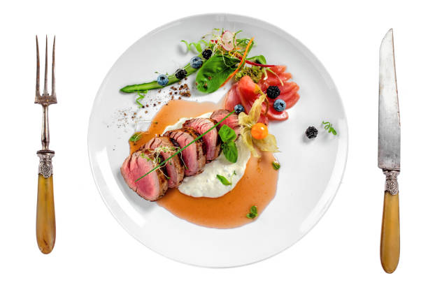 Medium rare meat steak Gourmet medium rare meat steak with sauce and fresh salad. Healthy meal made of meat fillet and fresh vegetables isolated on white background. Top view. white restaurant dishes stock pictures, royalty-free photos & images