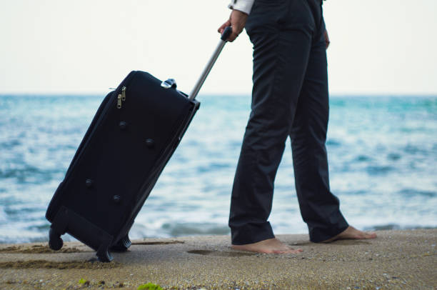 istock Walking businessman with valise on the beach 869098454